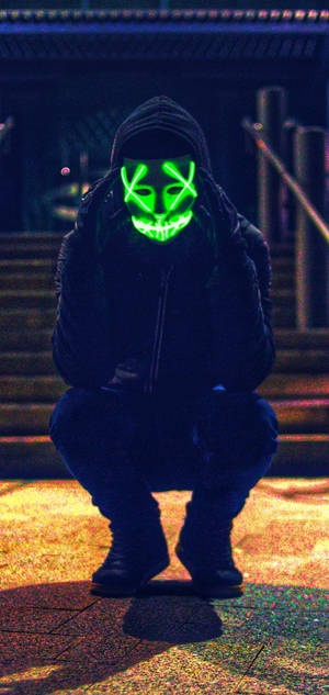 Fear Meets Mystery - A Man In A Chilling Purge Mask Crouched In Darkness Wallpaper