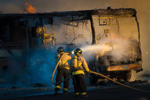 Firefighters Hosing Down A Bus Wallpaper