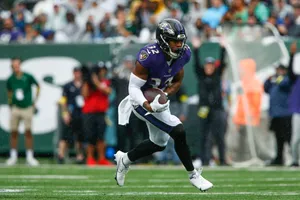 Football Player Running During Game Rainy Weather Wallpaper
