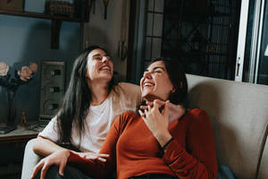 Friendship Of Two Women On Couch Wallpaper