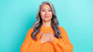 Grateful Middle Aged Woman Orange Sweater Wallpaper