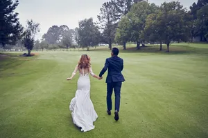 Groom And Bride Running On Golf Course Wallpaper