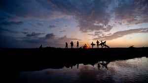 Group Of Friends Beside The Lake With Bonfire Wallpaper