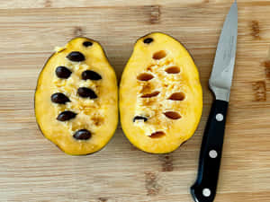 Halved Pawpaw With Seeds And Knife Wallpaper