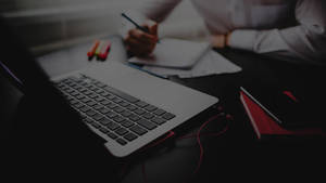 Hardworking Man Writing On Office Desk Wallpaper