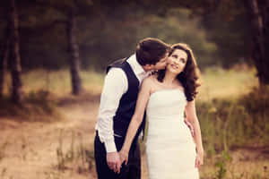 Husband And Wife Cheek Kiss On Grass Wallpaper