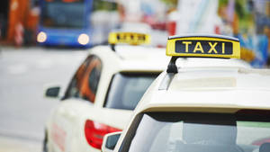 Iconic Black And Yellow Taxi With Rooftop Sign In A Cityscape Wallpaper