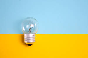 Illuminated Light Bulb Against Bright Background Wallpaper