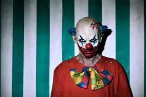 Intimidating_ Clown_ Against_ Striped_ Background.jpg Wallpaper