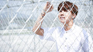 J-hope Holding On A Fence Wallpaper