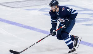 Jacob Trouba Gliding On Ice While Holding Hockey Stick In Front During Game Wallpaper