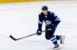 Jacob Trouba Gliding On Ice With Raised Hockey Stick Wallpaper