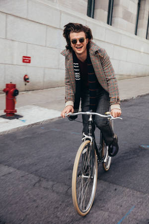 Joe Keery Riding A Bike Wallpaper