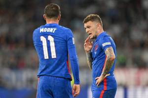 Kieran Trippier Engaging In A Discussion With Fellow Teammate On The Field Wallpaper