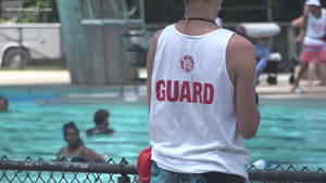 Lifeguard Vigilantly Overseeing A Swimming Pool Wallpaper