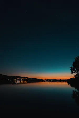Lit Buildings Near Lake Under Starry Evening Sky Wallpaper