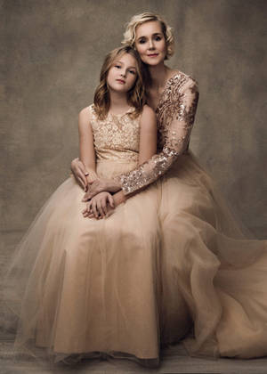 Loving Mother And Daughter In Matching Elegant Gowns Wallpaper