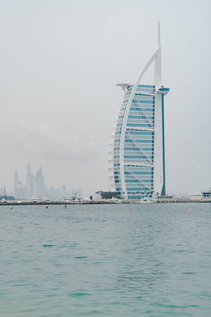 Majestic Burj Al Arab Against A Refreshing Pastel Blue Sky Wallpaper