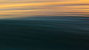 Majestic Golden Sunrise Over The Serene Blue Ocean Wallpaper