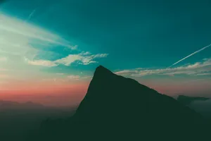 Majestic Mountains Surrounded By Billowing Clouds Wallpaper