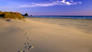 Majestic Sandy Beach Under A Vibrant Sunset Wallpaper