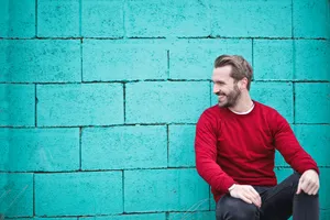 Male Pose Against Blue Brick Wall Wallpaper