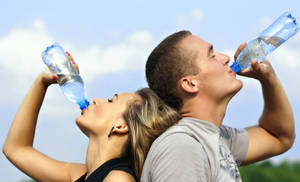 Man And Woman Drinking Water From Bottles Wallpaper