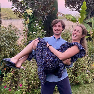 Man Carrying Womanin Garden Wallpaper