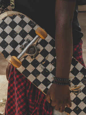 Man Holding Checkered Skateboard Wallpaper