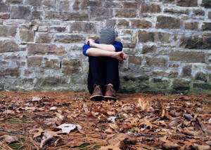 Man Sitting Alone Against Brick Wall Wallpaper