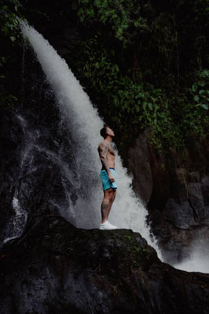 Man Standing By The Falling Water Wallpaper