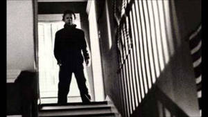 Michael Myers Menacingly Appearing At The Top Of The Stairs In A Suspenseful Scene Wallpaper