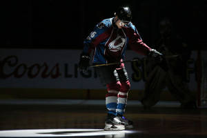 Mikko Rantanen Holding Hockey Stick Under Spotlight Wallpaper