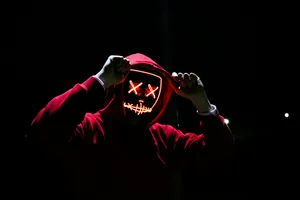 Mysterious Hooded Figurewith Neon Mask4k.jpg Wallpaper