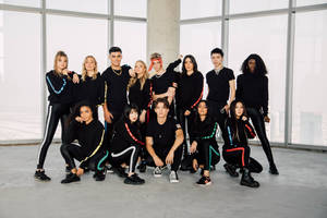 Now United Members Showcasing Unity And Diversity In Black Attire Wallpaper