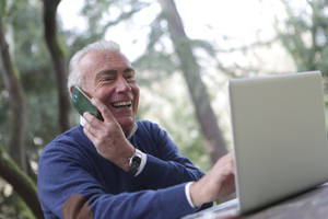 Old Man Laughing On Laptop And Phone Wallpaper