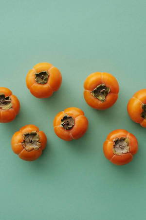 Persimmon Fruit On Green Minimalist Backdrop Wallpaper