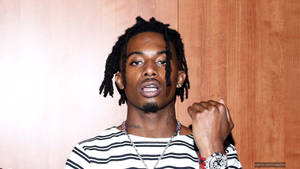 Playboi Carti Holds Fist Up In Adrenaline And Progress. Wallpaper