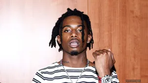 Playboi Carti Holds Fist Up In Adrenaline And Progress. Wallpaper