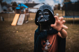 Powerful Sith Lord Posing With Red Lightsaber Wallpaper