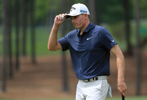 Pro Golfer Aaron Wise Holding His Cap In A Contemplative Moment Wallpaper