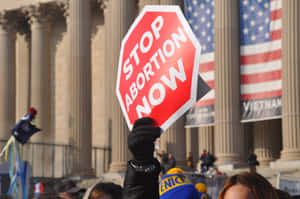 Protester Holding A 'stop Abortion Now' Placard Wallpaper