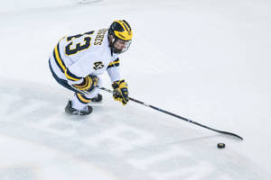 Quinn Hughes Leaning Forward While Dribbling Hockey Puck Wallpaper