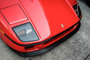 Red Ferrari Sports Car Silhouetted Against A Dramatic Sunset Wallpaper