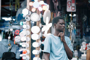 Reflective Man Contemplating Amidst The Lights In Sierra Leone Wallpaper