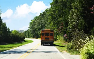 School Bus Traveling On Road Back View Wallpaper