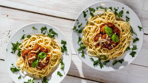 Scrumptious Italian Pasta Served On Two Plates Wallpaper