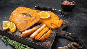 Scrumptious Wiener Schnitzel Served With Lemon Wedges And Parsley Garnish Wallpaper