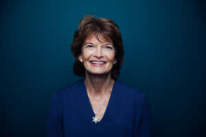 Senator Lisa Murkowski Smiling Against A Blue Aesthetic Background Wallpaper