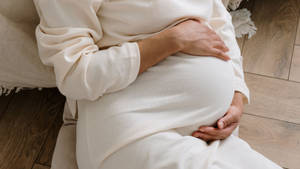 Serene Pregnant Woman In White Attire Wallpaper